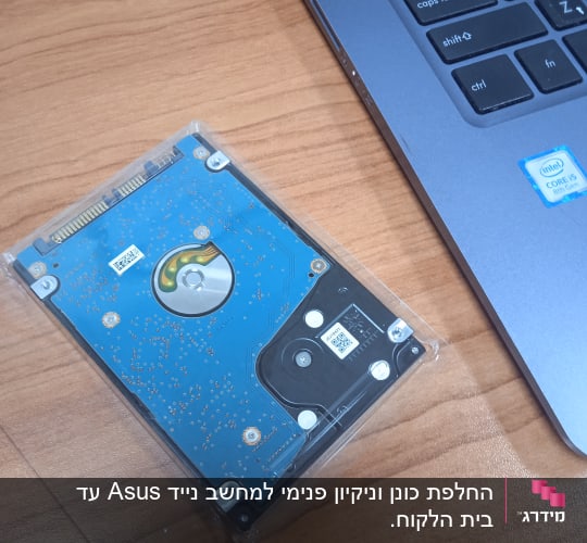 מחשב נייד ודיסק קשיח על שולחן עץ
